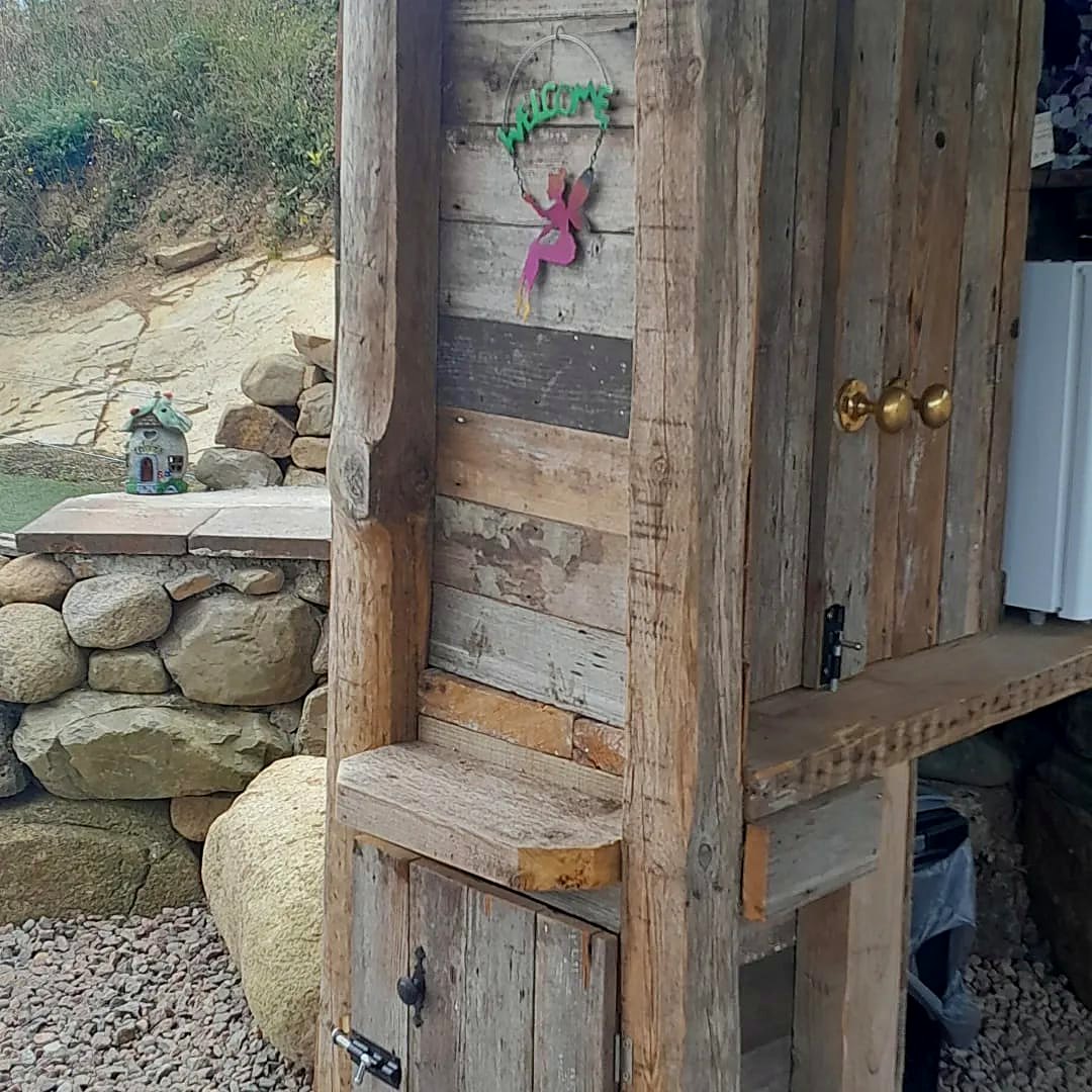 Weathered timber door with a little fairy sign, set into the stone walls