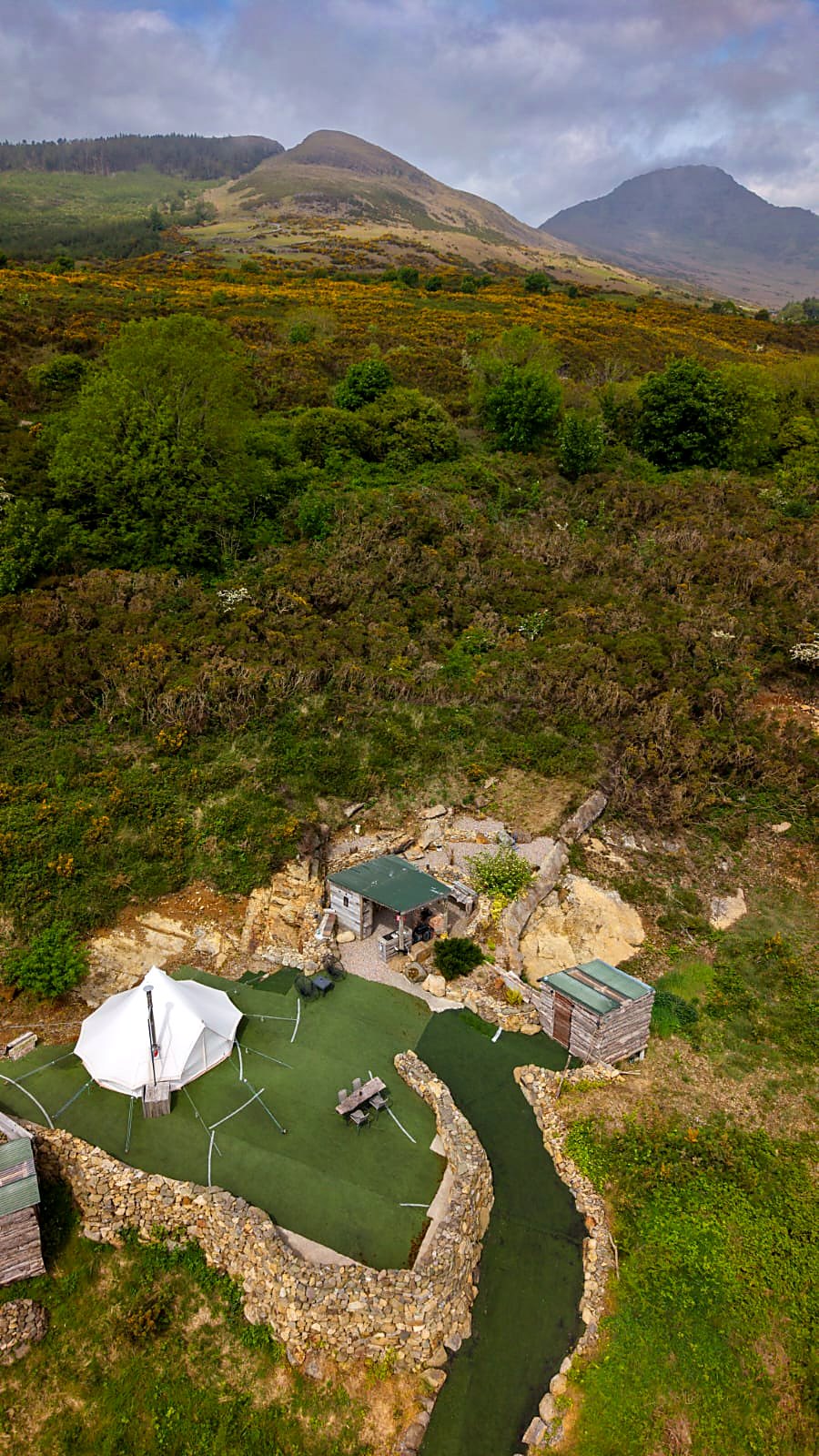 Fairy Hill from above — the bell tent on its walled lawn with the mountains behind