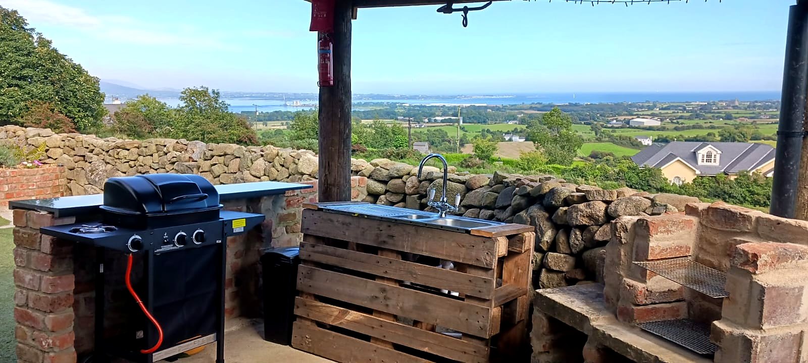 Outdoor kitchen at Fairy Fort with gas BBQ, sink and stone-built charcoal BBQ looking over Carlingford Lough