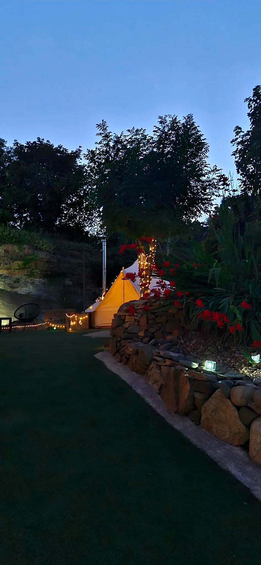 Fairy Cove glowing warm at dusk behind a stone wall strung with fairy lights