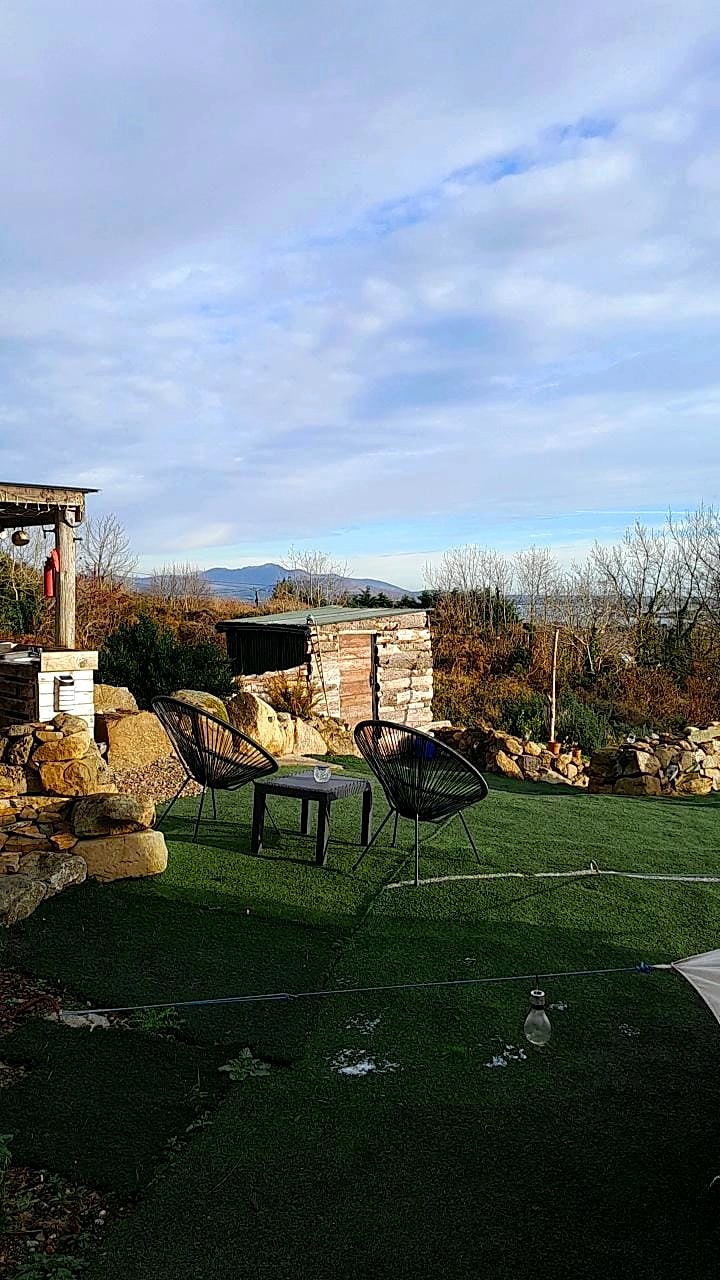 Two chairs and a small table on Fairy Hill's private lawn with stone walls and the Mourne Mountains beyond