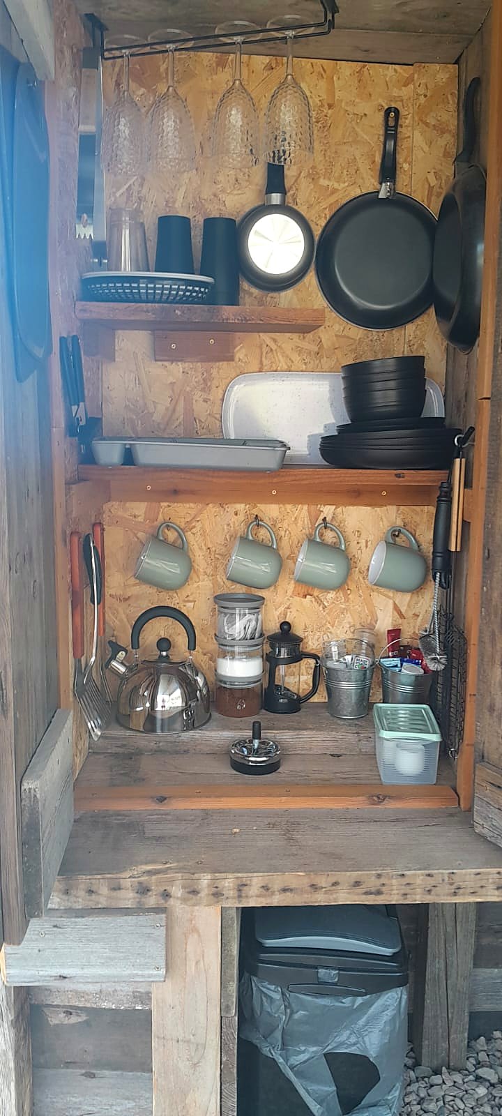 The kitchen dresser stocked with pans, plates, mugs and a kettle