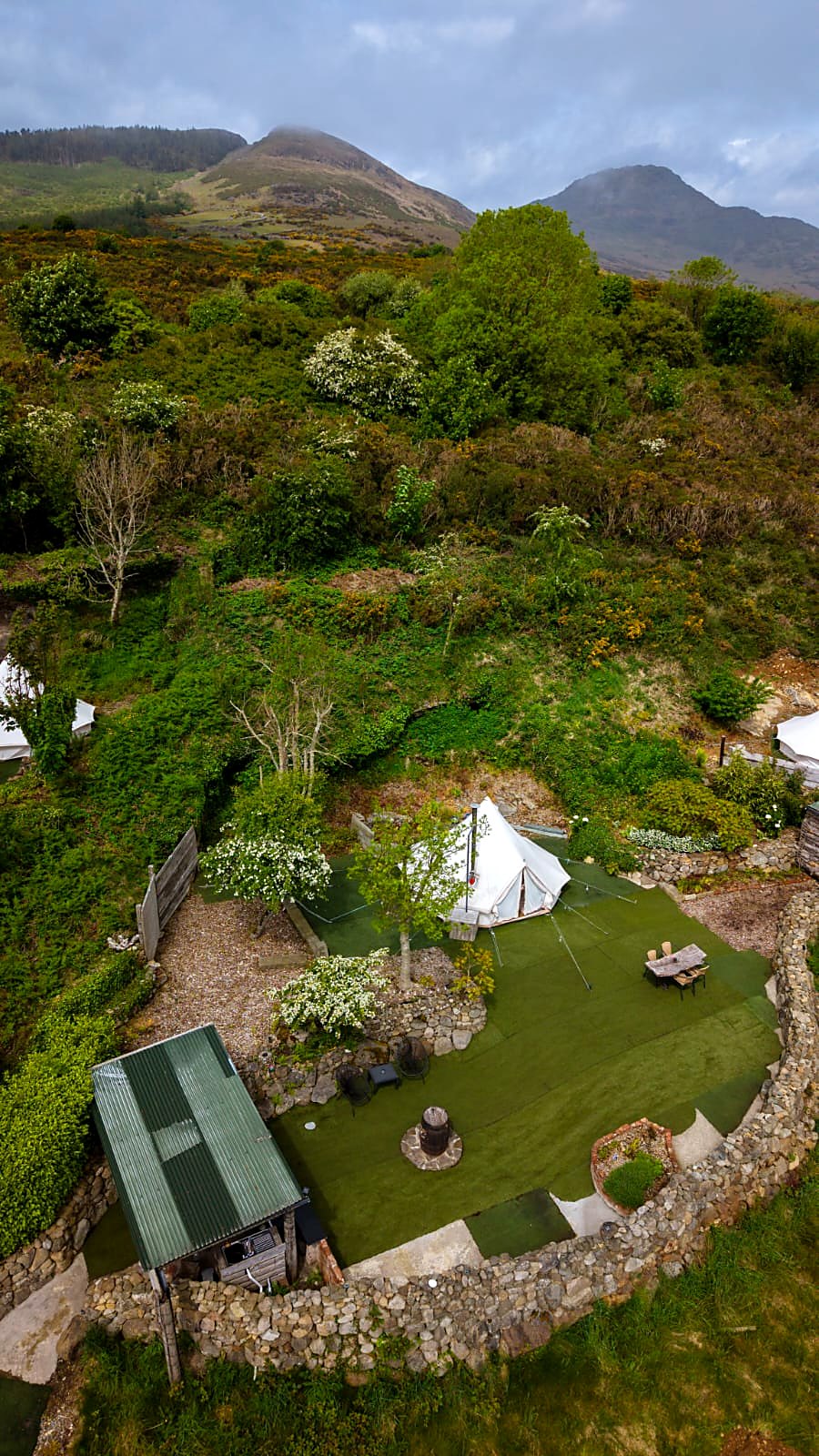 Fairy Fort seen from above at Rosemount Glamping — the bell tent on its walled lawn with the Cooley hills and Mourne Mountains behind