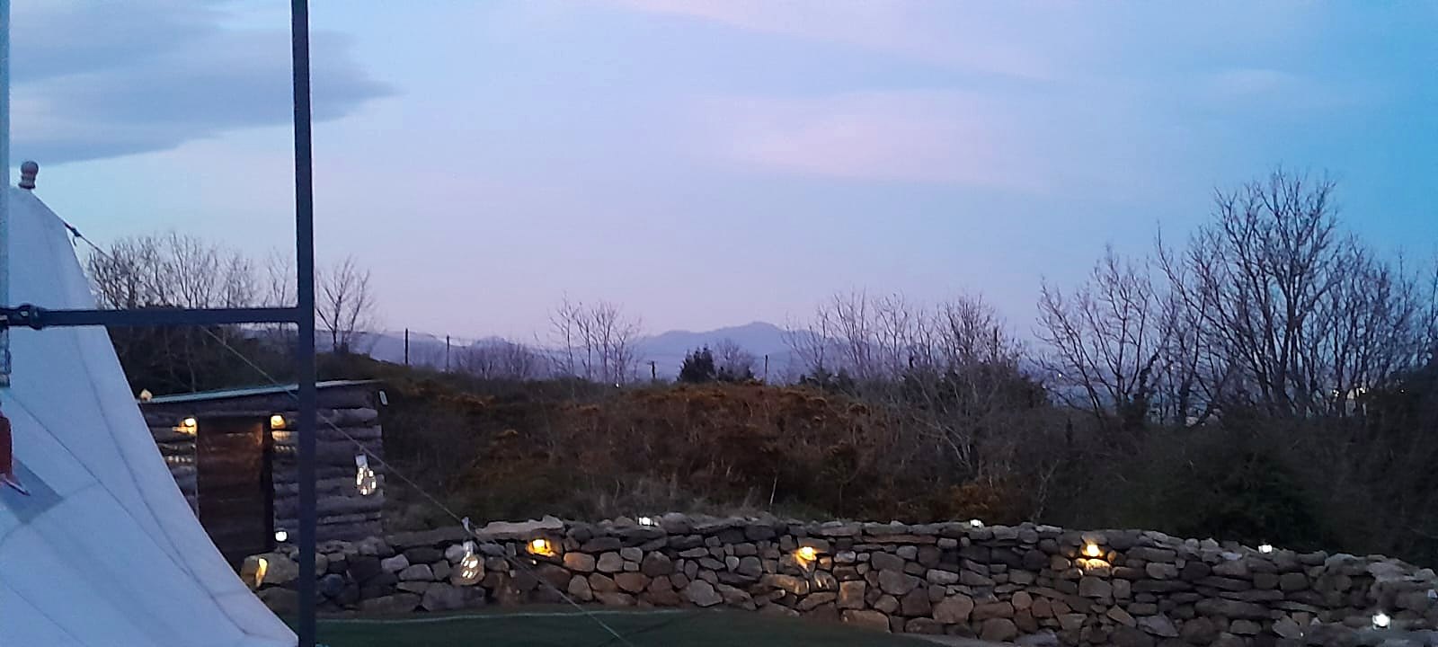Stone wall lit with small lights at dusk, the mountains on the skyline