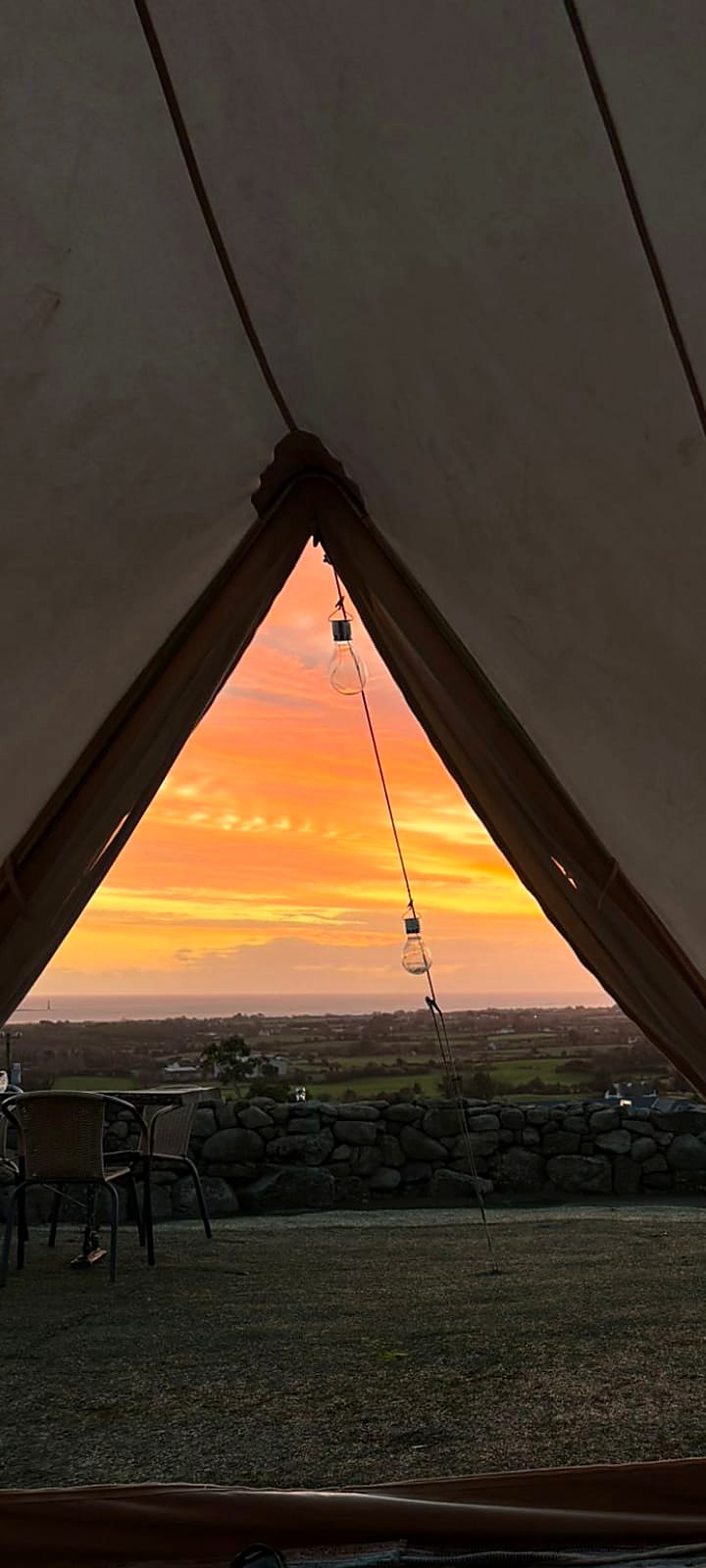 Orange sunrise over the fields and sea seen from inside Fairy Fort through the open doorway
